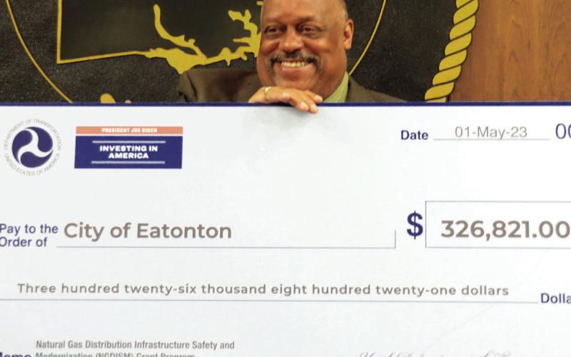 Following the May 7 city council meeting, Eatonton Mayor John Reid posed with a symbolic $326,821 check from the U.S. Dept. of Transportation as part of its Natural Gas Distribution Infrastructure Safety and Modernization grant program, intended to help cities and municipalities replace aging and deteriorating natural gas delivery systems. Reid said he greatly appreciates the help from federal authorities to advance Eatonton’s ongoing modernization efforts. IAN TOCHER/Staff