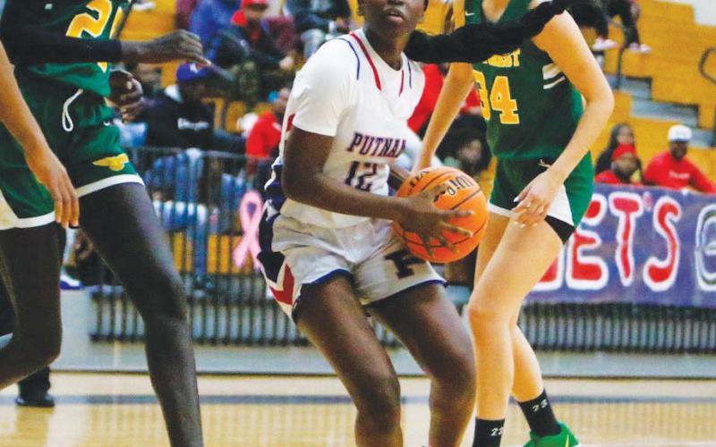 Putnanm sophomore Eriyana Little (12) makes her way through the way trying to attempt a layup over a Greenforest defender. LANCE McCURLEY/Staff