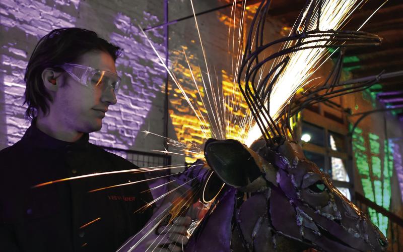 Sparks fly as noted Lake Country metal sculptor Brian Dawson works on a sculpture during the 6th annual Artigras event last Saturday night at The Livery in downtown Eatonton. IAN TOCHER/Staff