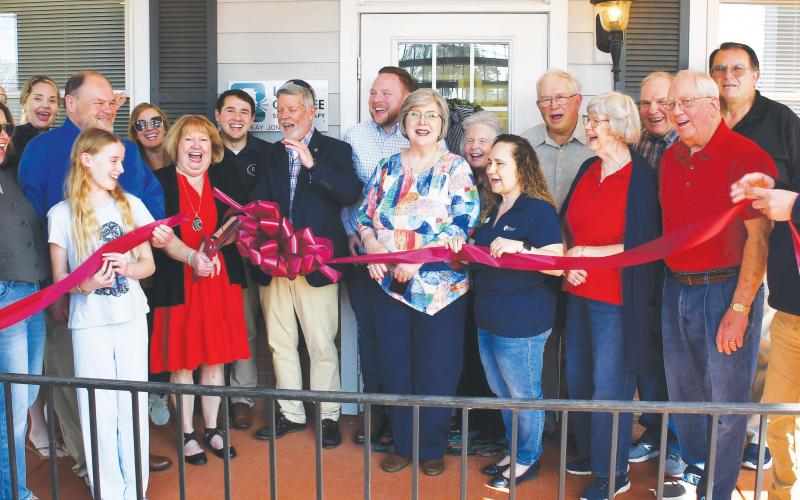 Licensed speech therapist Kay Jones (red dress), owner of Lake Oconee Speech Therapy, cuts the ribbon flanked by her husband and son as other members of her Lake Country community cheer the official opening of her facility at 951 Harmony Rd., Ste. 103, Eatonton. IAN TOCHER/Staff
