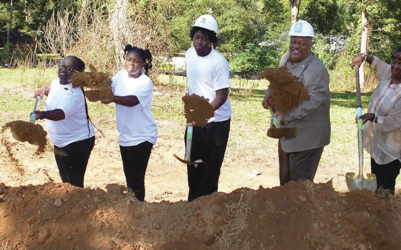 Flanked by Putnam Habitat for Humanity board member Jack McDonald and her children, Barbara Monday (second from left) was all smiles as she participated Monday in the official groundbreaking ceremony for her new home to be completed by early next spring on South Madison Street in Eatonton.