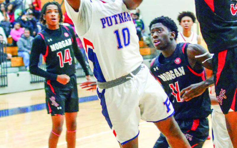 Putnam County’s Tamaud Woodson (10) attempts to make a layup over a Morgan County defender in last week’s win over the Dogs. IAN TOCHER/Staff