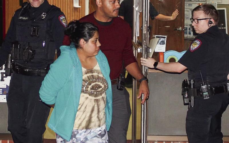 Reyna Lopez, front center, is escorted by Eatonton Police Department officers, from left, Chris Detweiler, Investigator Hargrove Jones and Officer Jeremy McLure, who are taking Lopez to jail at Putnam County Sheriff’s Office. CONTRIBUTED/EPD