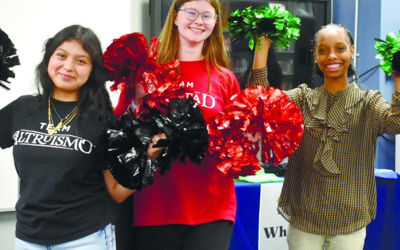 House leaders Mishel Perez, Peyton Stokes, and Alexis Evans cheer during the house sorting ceremony.