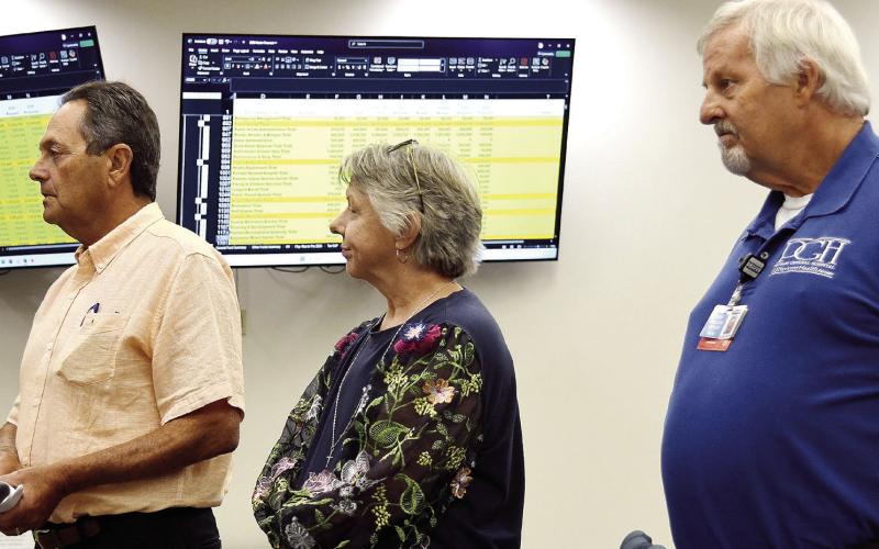 L-R: Putnam General Hospital Authority Board member Lou Benjamin, PGH Human Resources Director Rhonda Largo, and hospital CEO Alan Horton address county commissioners with detailed financial stats displayed on screens behind them. IAN TOCHER/Staff