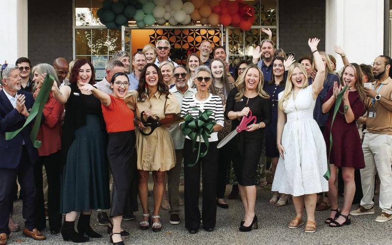 With plenty of support from friends and colleagues, Jackie Greer (center with black scissors) made the official ribbon cut for her new space for Greer Force Marketing at 1001 Village Park Dr., Unit 108, in Greensboro. IAN TOCHER/Staff