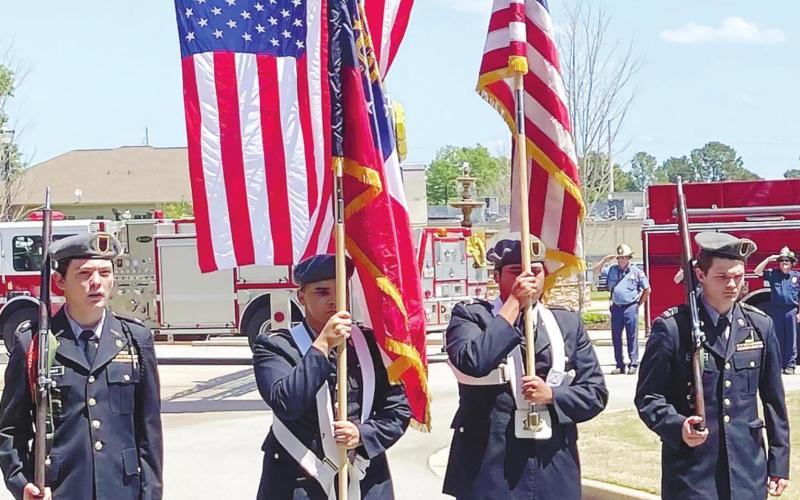 Members of the Putnam County High School JROTC color guard present the flag as members of the Putnam County Fire Department salute in the background. CONTRIBUTED