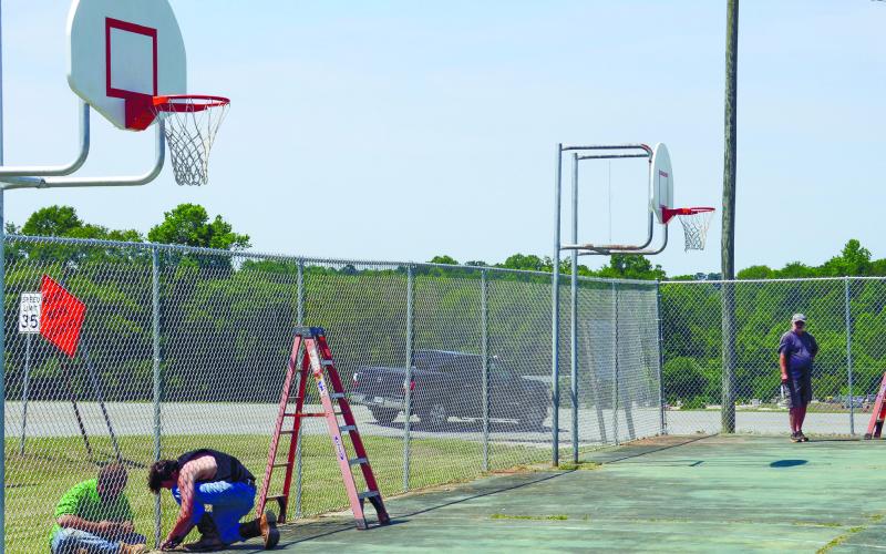 Putnam County contract workers put the finishing touches on a new fence last Wednesday, surrounding the basketball courts at Jimmy Davis Park. IAN TOCHER/Staff