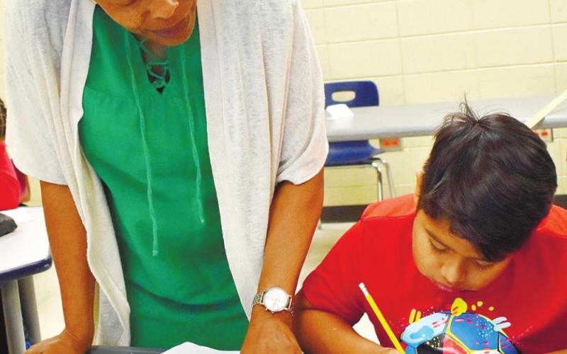 Teacher Bernice Grant helps sixth-grader Alex Ramirez Alday fill out the check registry.