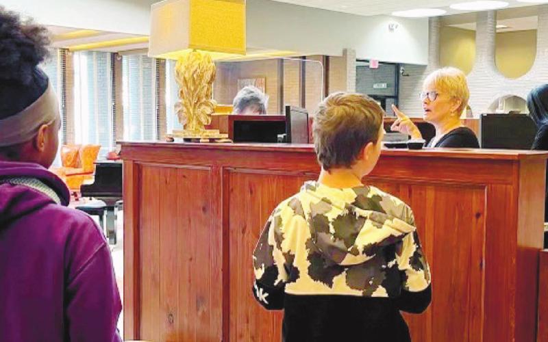 Trinity Dunn and David Johnson listen to a bank clerk’s instructions.