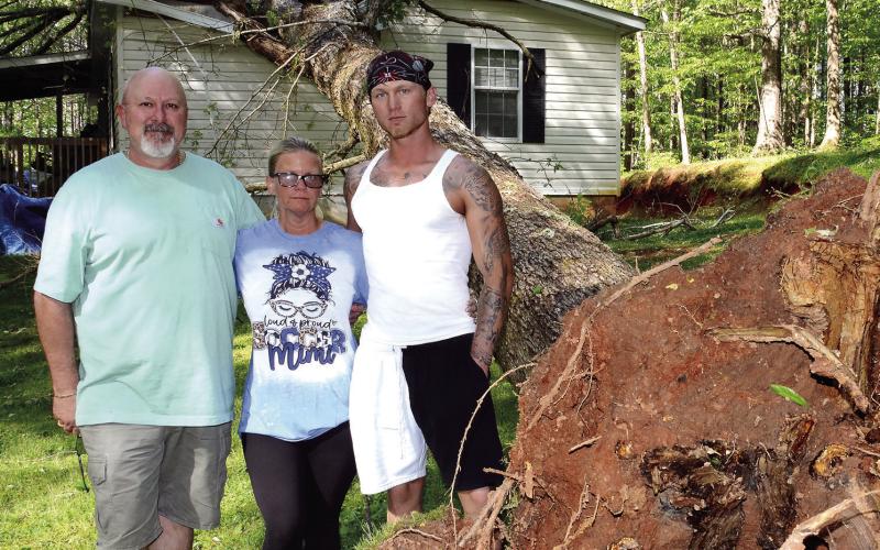 Johnny and Kimberly Johnson stand with their son, Branson, who narrowly escaped injury when a large tree fell directly over his bed in April. IAN TOCHER/Staff