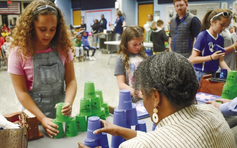 A Speed Stack Club member shows board member Simone Jones how to stack the cups. BAILEY McCULLY/Staff