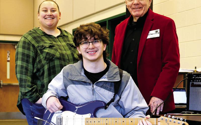 Baldwin High School music teacher Robyn Meeks, Milledgeville First Methodist Church music minister John Cotton, and Baldwin High School student Kyle Camilla pose for the Putnam Christian Outreach Angel Tree presentation of a Fender Squire Stratocaster electric guitar. CONTRIBUTED