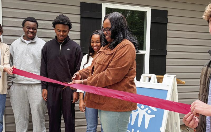 L-R: Habitat for Humanity of Putnam’s Katherine Mahlberg with new homeowners Jaevien, Khaleb, Amyah, and Candice Ellison cutting the ribbon May 12, as GCSU student and HFHP volunteer Zach Zachry keeps it tight. IAN TOCHER/Staff