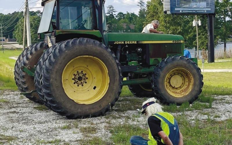 Paul Matthew Kroening sits handcuffed beside the tractor he is accused of stealing as the tractor’s owner, Tim Camp, checks it out. Sheriff Howard Sills pulled the tractor over on Lake Oconee Parkway near Anchors Marina. CONTRIBUTED