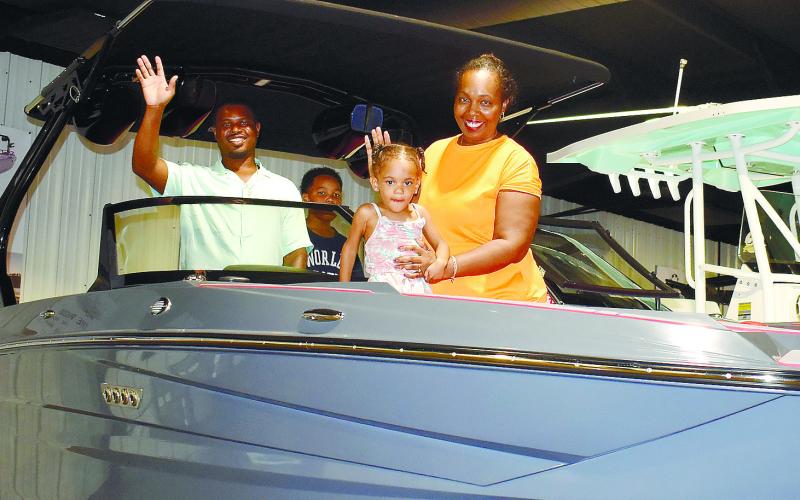 Stella Collins and her young daughter Denver enjoy checking out a new boat on display at The Boat Shop with Rafeal Jernigan and Demaras Collins.