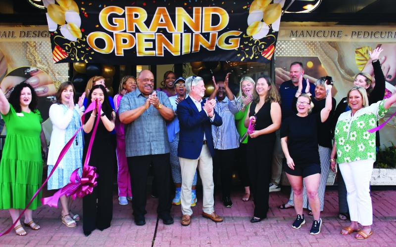 Eatonton Mayor John Reid (grey shirt) and his wife, Janie, joined Eatonton-Putnam Chamber of Commerce President Robbie King (center) in welcoming business owner Jennifer Nguyen (with scissors) to a ribbon-cutting ceremony for Sassy Nails, a full-service hand-and-foot spa now open at 117 S. Jefferson Ave. in downtown Eatonton. IAN TOCHER/Staff