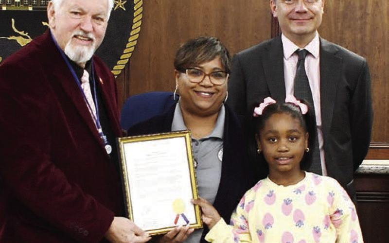 L-R: Last Tuesday, County Commission Chairman Bill Sharp awarded County Public Information Ocer Stephanie McMullen, with her daughter Reese, an ocial recognition of Feb. 20 as Government Communications Day, alongside Commissioner Richard Garrett and the rest of the board. IAN TOCHER/Staff