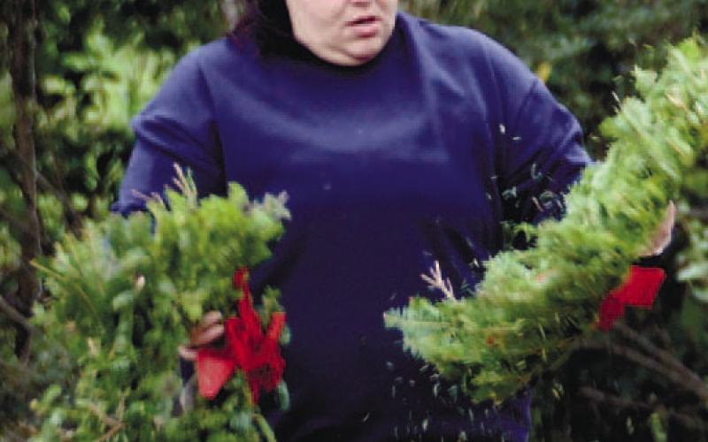 Putnam County VFW Commander Nikki Barker shakes stray needles from wreaths before laying them in tribute on Eatonton veterans’ graves. IAN TOCHER/Staff