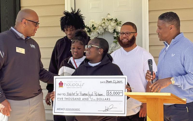 Barbara holding her $5,000 down-payment assistance check from the “Homes for the Holidays” program from Warrick Dunn Charities.  EMME CLAUSE/Staff