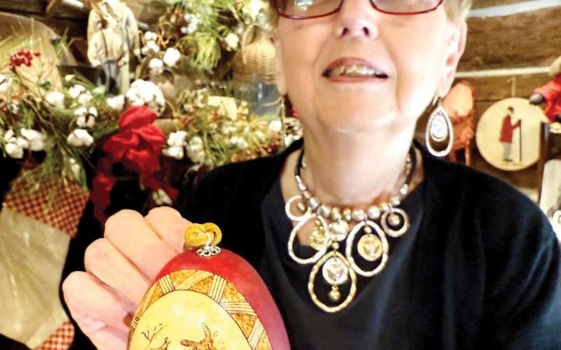 Uncle Remus Museum gift shop manager Lynda Walker displays a locally sourced, hand-painted Christmas ornament depicting ‘Brer Rabbit. IAN TOCHER/Staff