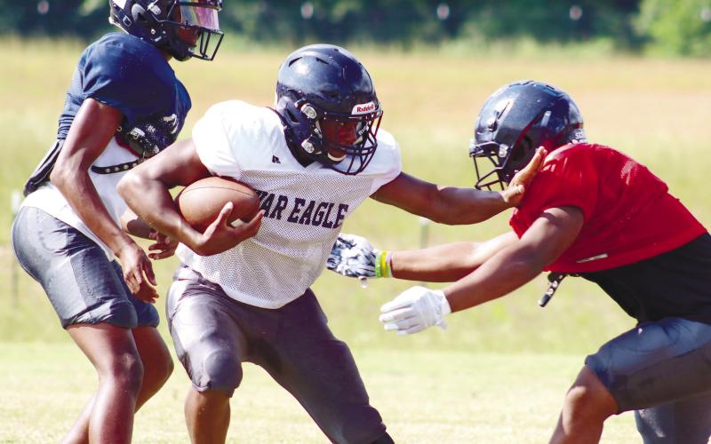 Putnam County rising sophomore running back Omarion Butts (white) stiff arms a defender. LANCE McCURLEY/Staff