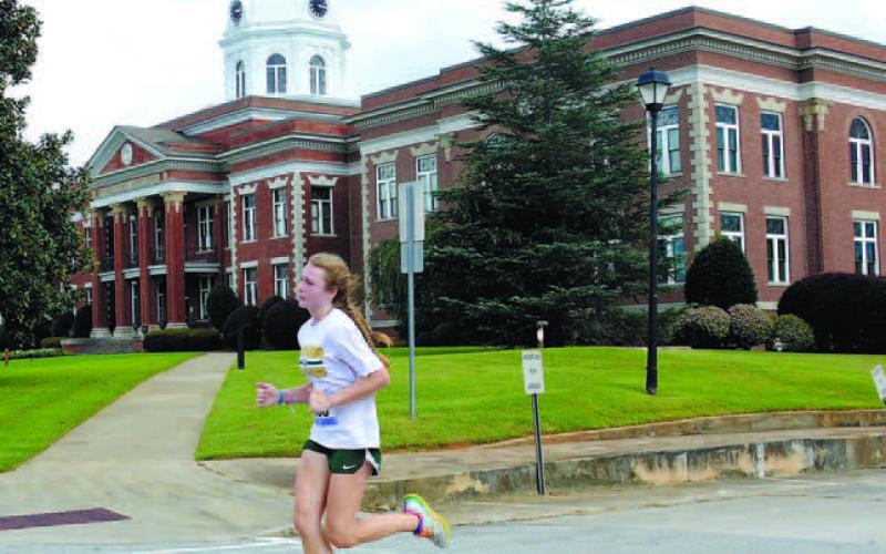 Court date: Gatewood 10th grade student Ansleigh Hillin, 15, runs past the historic Putnam County courthouse in downtown Eatonton before eventually finishing as the womens’ class winner of Gatewood’s annual Swamp Stomp 5K. IAN TOCHER/Staff