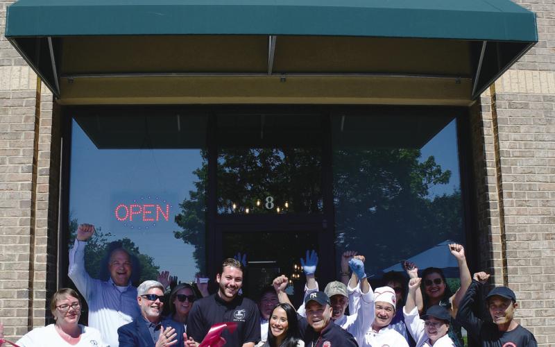Pho &amp; More co-owner Marino Graf (with scissors) stands with his wife, Summer, her father, John Nguyen, and the couple’s daughter while friends and employees help them celebrate during a ribbon-cutting ceremony hosted by the Eatonton-Putnam Chamber of Commerce. IAN TOCHER/Staff