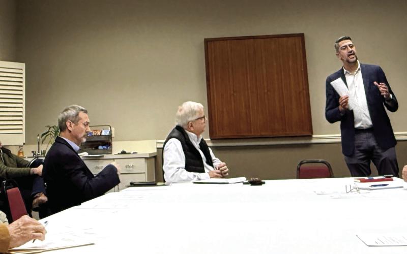 Joel Wiggins (standing), managing partner of the Southern Group of Georgia and a representative of the C-PACE Alliance, addresses members of the Lake Oconee Area Development Authority last Thursday at Farmers &amp;amp; Merchants Bank on Lake Oconee Parkway. Melody Echols, program administrator with Peach State C-PACE, is seated at left. IAN TOCHER/Staff