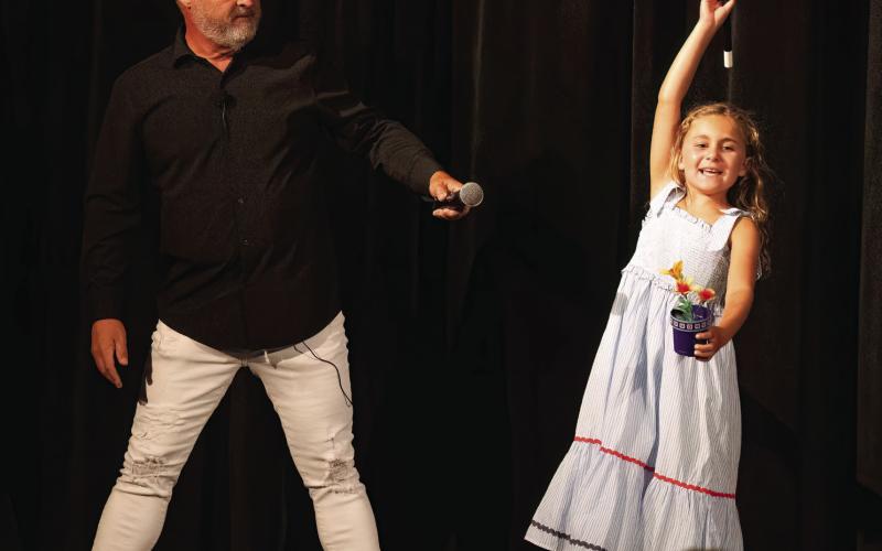 Mark the Magic Man’s daughter performs a trick from the magic wand that produces flowers. She learned this trick at his magic camp. LEIGH LOFGREN/Staff