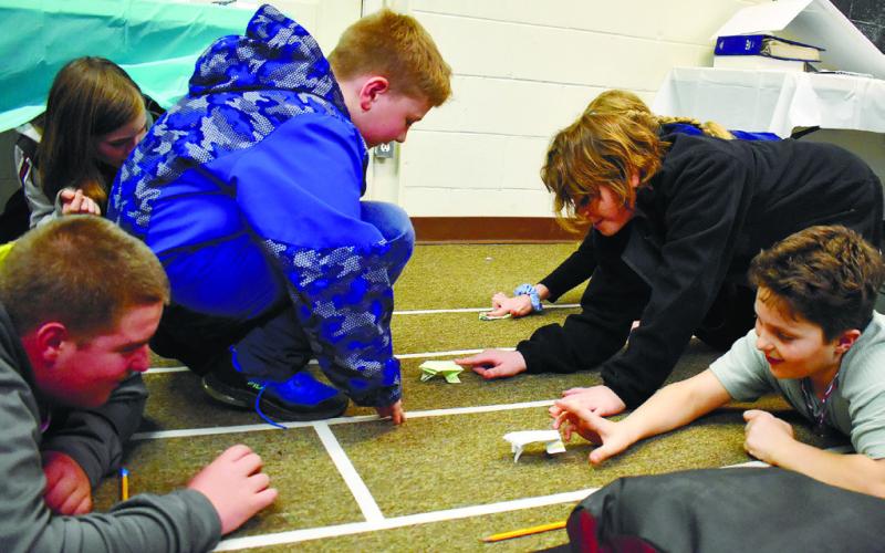 Three teams put their origami frogs to the test in the race trying to see which one will leap farther and faster.