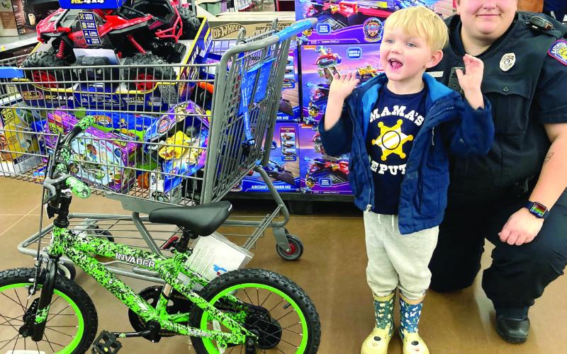 Emmeitt Howell, 5, excitedly talks about the toys in his shopping cart that Officer Rebecca Meeks helped him find at Walmart last week. LYNN HOBBS/Staff