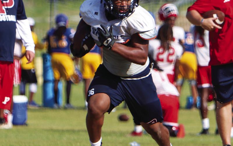 Elijah Dunn carries the ball for Putnam County during a padded camp in Eatonton ahead of the 2024 season. LANCE McCURLEY/ Staff