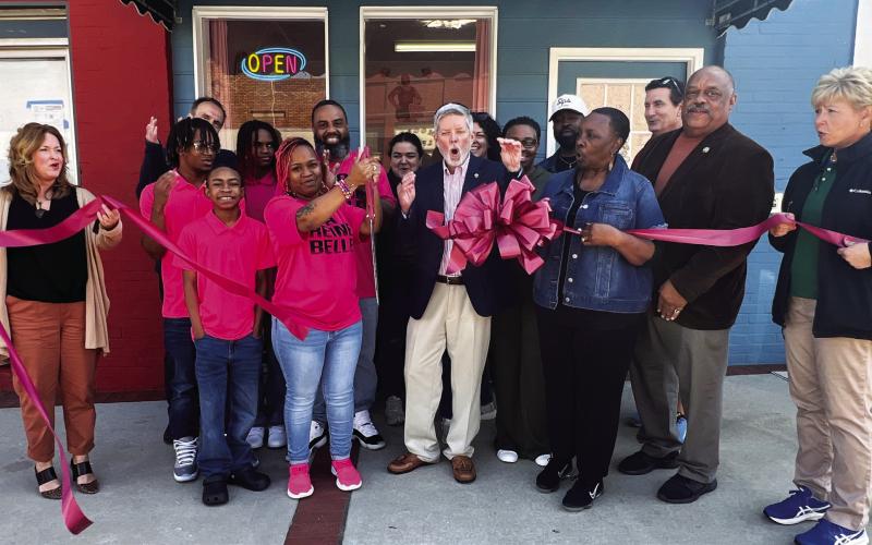 Eatonton-Putnam Chamber of Commerce President Robbie King (center) reacts with surprise as La Reine Belle owner Robin Williams cuts the ribbon to officially open her bakery in downtown Eatonton. Beside King is Eatonton City Councilmember Janie Reid and her husband, Mayor John Reid, who was instrumental in bringing Williams and her business to the city.