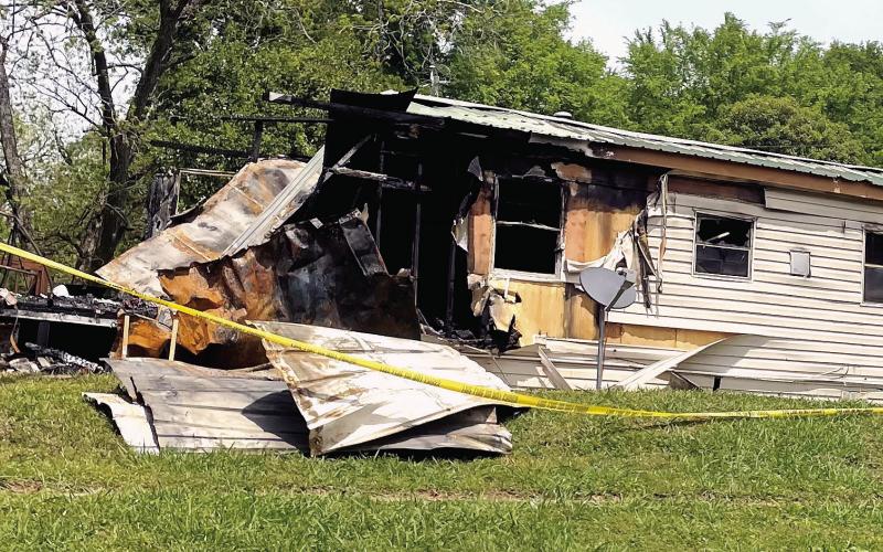 Yellow crime tape surrounds the burned mobile home on East Marion Street Monday. The left side of the home was completely burned away, and the rest of the interior gutted and/or charred by the flames. LYNN HOBBS/Staff
