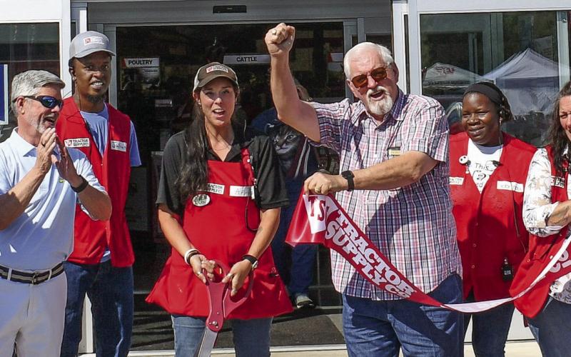 Eatonton-Putnam Chamber of Commerce President Robbie King (second from left) and Putnam County Commission Chairman Bill Sharp flank Tractor Supply store manager April Smith after she cut the ribbon on Saturday to officially open the company’s new Eatonton location. IAN TOCHER/Staff