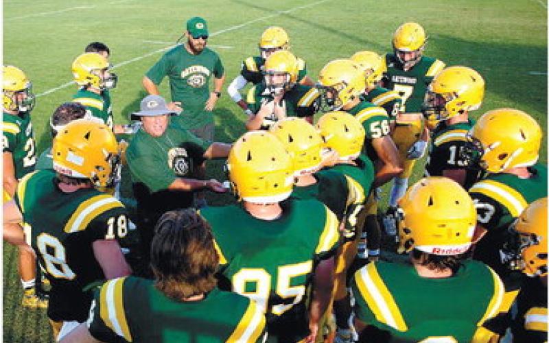Surrounded by an attentive team, Ratliff delivers advice and instruction during a pre-season scrimmage Aug. 5, at Gatewood's Sammons Field.