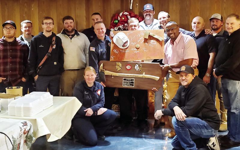 Eatonton Fire Department firefighters join for a photo with their recently-retired fire chief, Eugene Hubert (holding the plaques). CONTRIBUTED
