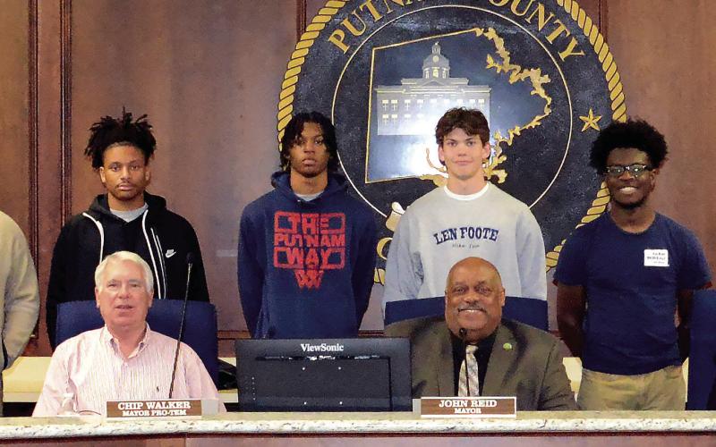 Twelve members of the 2024 Eatonton Youth Leadership Class from Gatewood and Putnam High Schools line up behind Eatonton City Council members during a Feb. 19 council meeting. IAN TOCHER/Staff