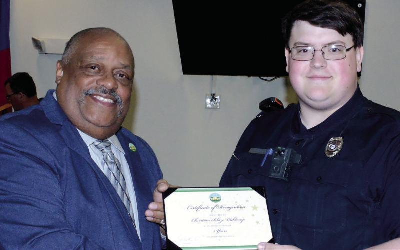 Before the start of the Feb. 6 city council meeting, Eatonton Police Officer Christian Waldroup (right) received a certificate of appreciation from Eatonton Mayor John Reid for five years of service. IAN TOCHER/Staff