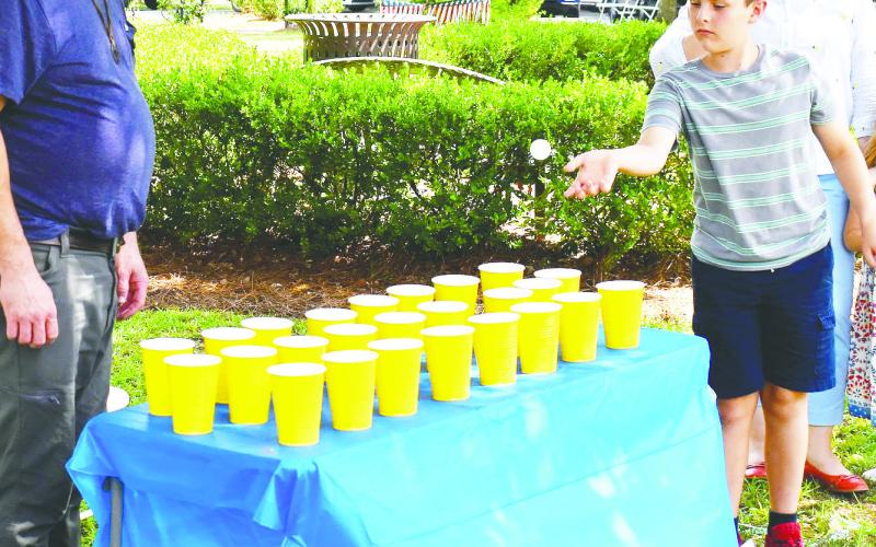Charlie Mock is throwing a ball trying to make is land in a cup and win a prize of cookies and candy. LENA HENSLEY/Staff