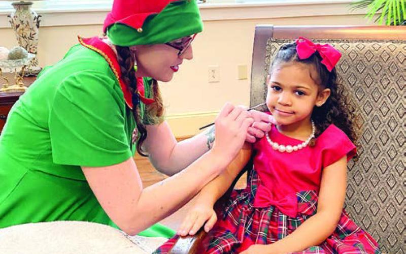 Landyn Austin, age 4, getting a cheerful snowman painted on her cheek by Phantom Face Paints. EMME CLAUSE/Staff