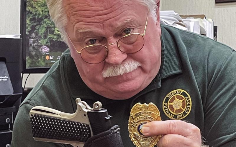 Putnam County Sheriff Howard Sills’ facial expression doesn’t hide his feelings on this holstered BB gun pistol and altered law enforcement badge used in several crimes in and around Putnam County. LYNN HOBBS/Staff