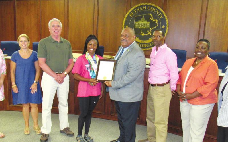 Putnam County High School rising sophomore and award-winning gymnast Karmyn Manning is presented a plaque by Eatonton Mayor John Reid and the City Council at their July 5 meeting. A proclamation read by Reid congratulated her for placing first All Around in her age group at the AAU Gymnastics National Championship in Springfield, Ill., earlier this month. MARK ENGEL/Staff