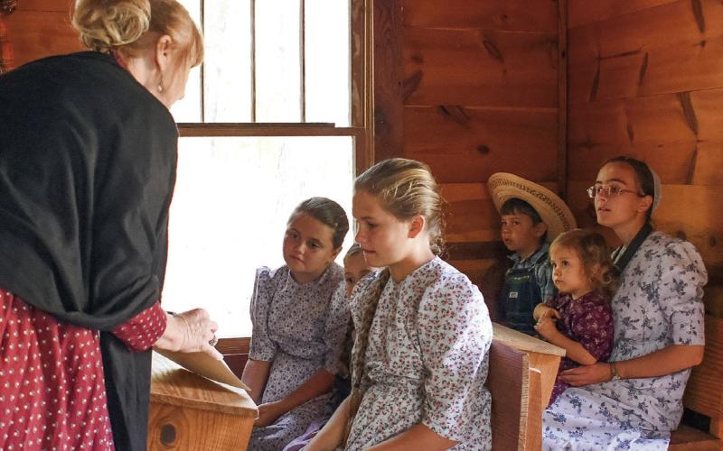 Lyn Romine (left) of Eatonton’s Historical Preservation Commission, served as Stepback’s school marm, instructing some young visitors who were also dressed in period-correct clothes. IAN TOCHER/Staff