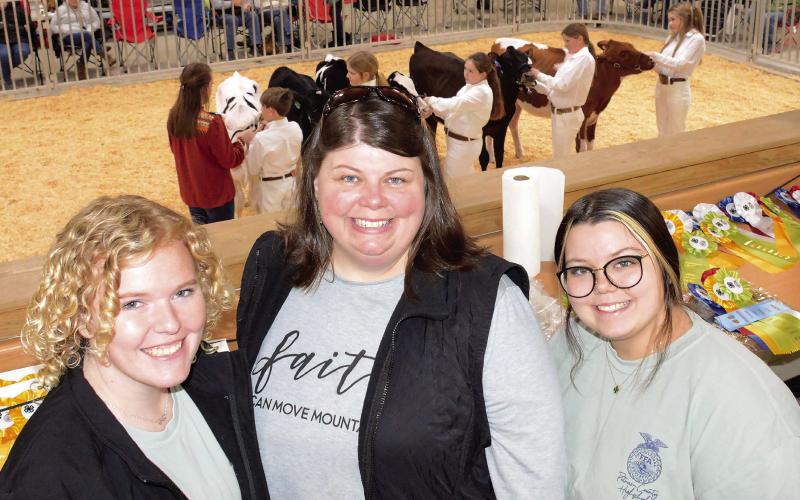 Flanked by UGA student Mackenzie Jones (left) and Putnam High School senior Kady Batchelor, PCHS Agriculture Education Advisor Kelly Smith managed the 17th annual Briar Patch Classic Dairy Heifer Show from an elevated position beside the show ring.