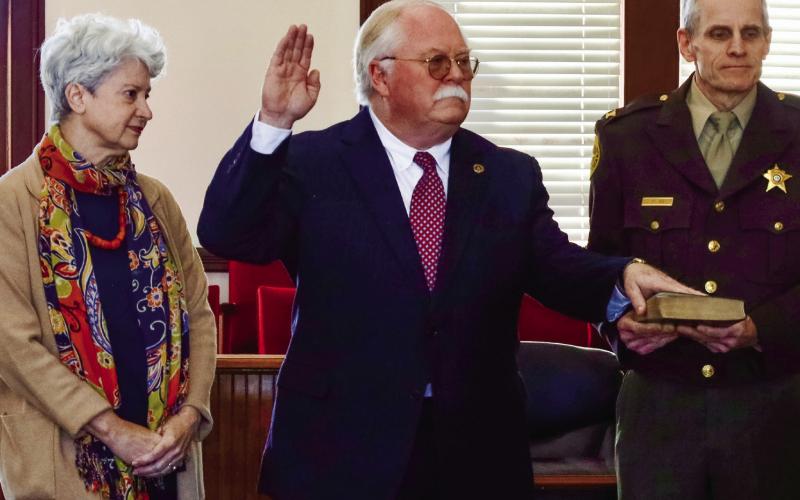 Janet Sills, left, watches as her husband, Putnam County Sheriff Howard Sills, is sworn in for another term. Chief Deputy Sheriff Col. Russell Blenk holds the Bible. CONTRIBUTED/Alyssa Martinez