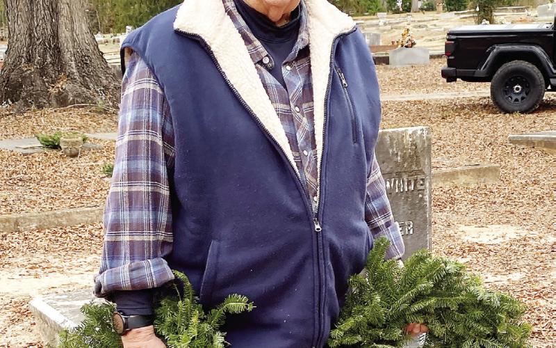 Former county commission chairman Billy Webster carries a pair of wreaths to place on veterans’ graves at Pine Grove Cemetery. EMME CLAUSE/Staff