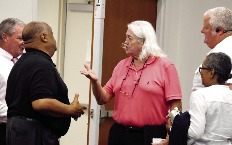Eatonton Mayor John Reid (left, in black) and citizen Don Sadler exchange words following last Tuesday’s Putnam County Commission meeting, with County Manager Paul Van Haute (far left), citizen Karen Garrett, and Putnam County Fire Chief Thomas McClain looking on. IAN TOCHER/Staff