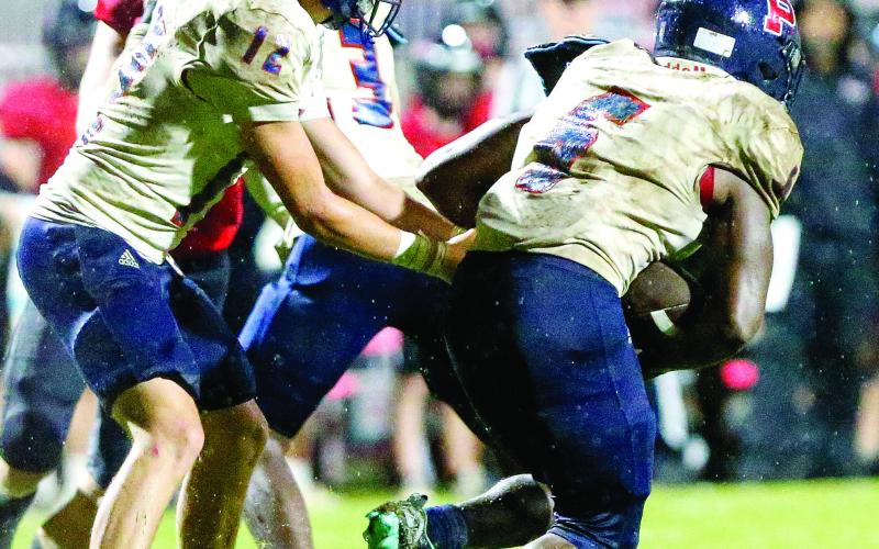 Putnam County quarterback Ethan Whatley (12) hands the ball off to running back Omarion Butts (6) during a game against Morgan County on Friday, Aug. 22. LANCE McCURLEY/File photo